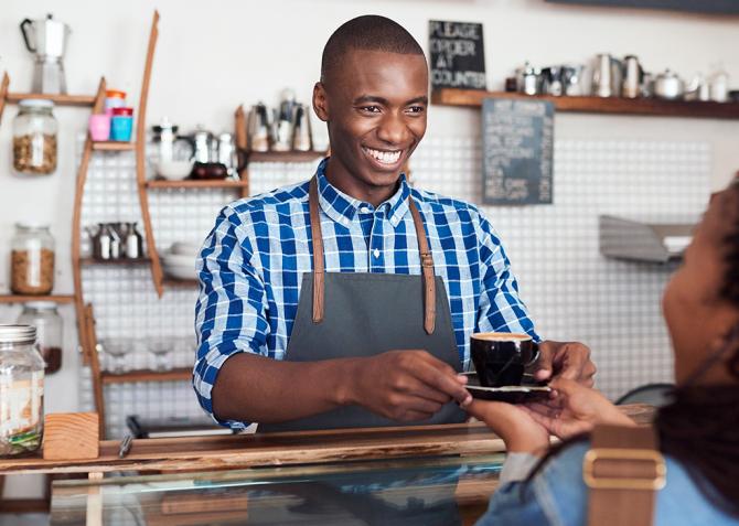 A server hands a cup of coffee to a customer.