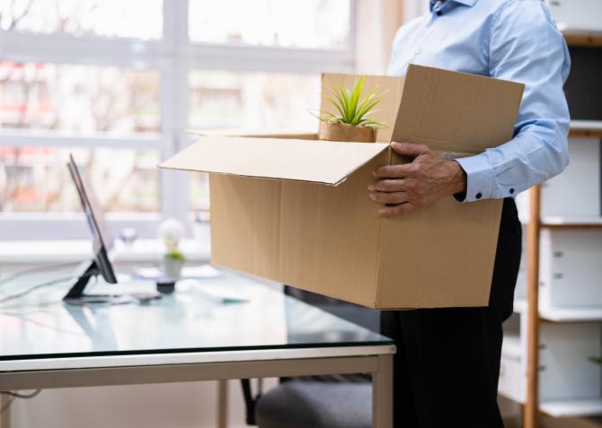 man packing up desk with cardboard box