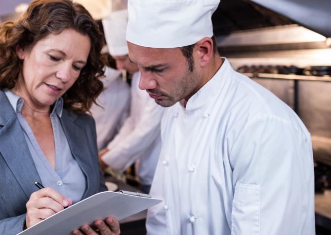 Restaurant owner talks over notes with chef