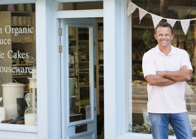 Man stating in front of small business storefront. 