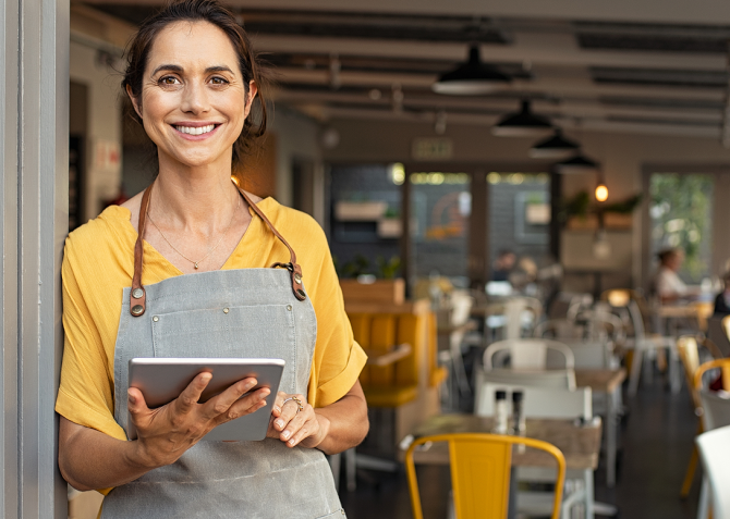 Female business owner smiling in front of store. 