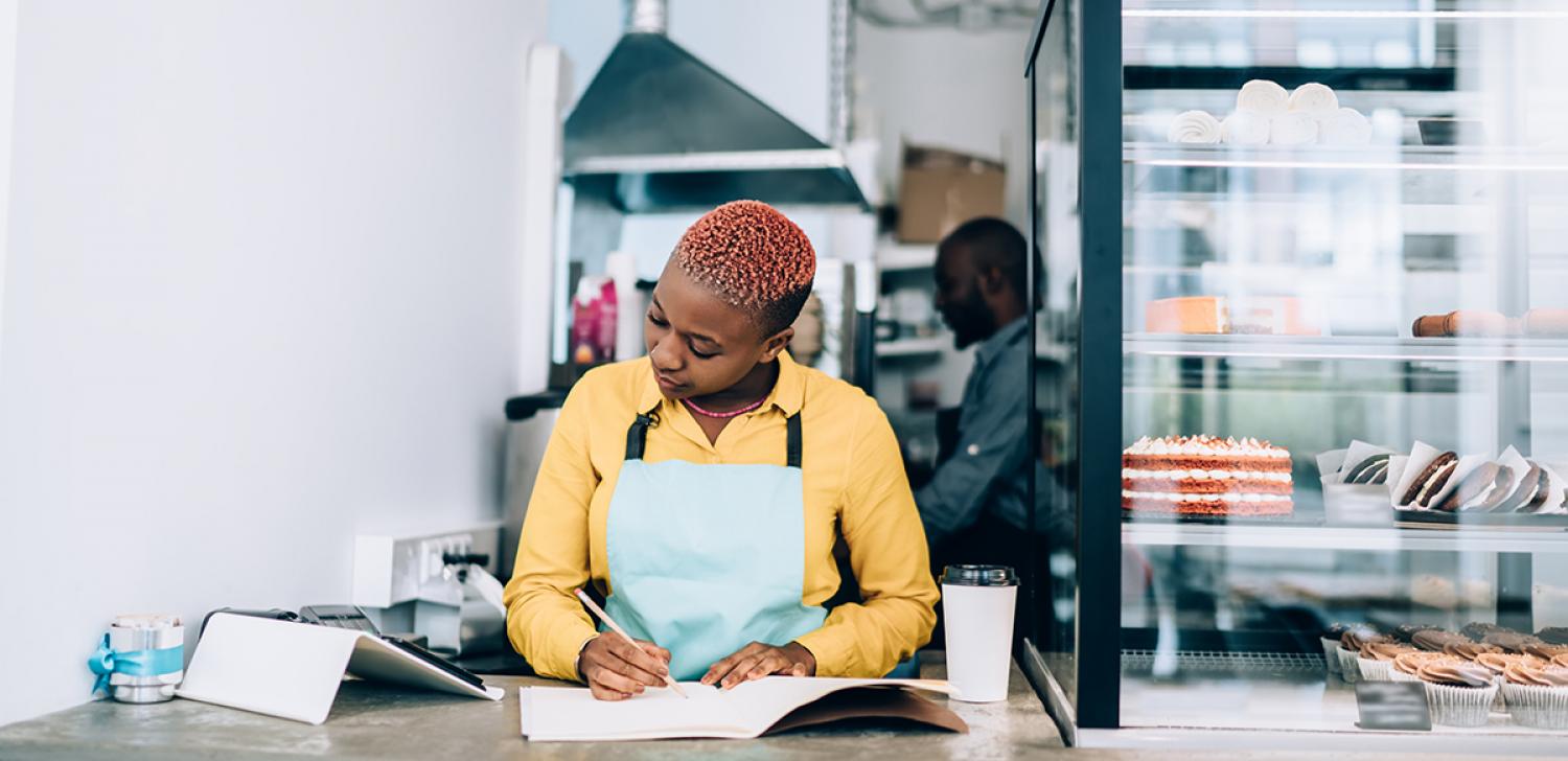 A small business owner tracks expenses while looking at a tablet device.