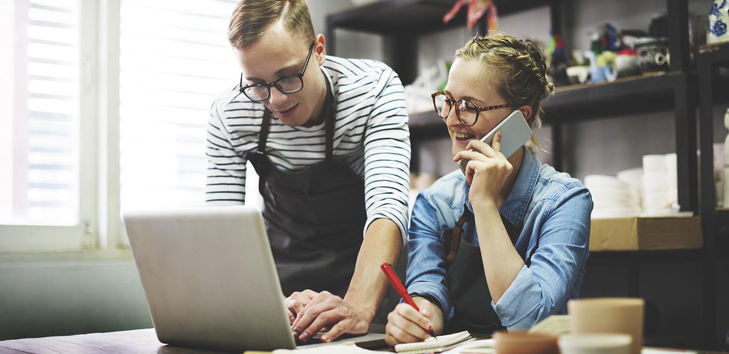 Two small business partners look at a laptop together.