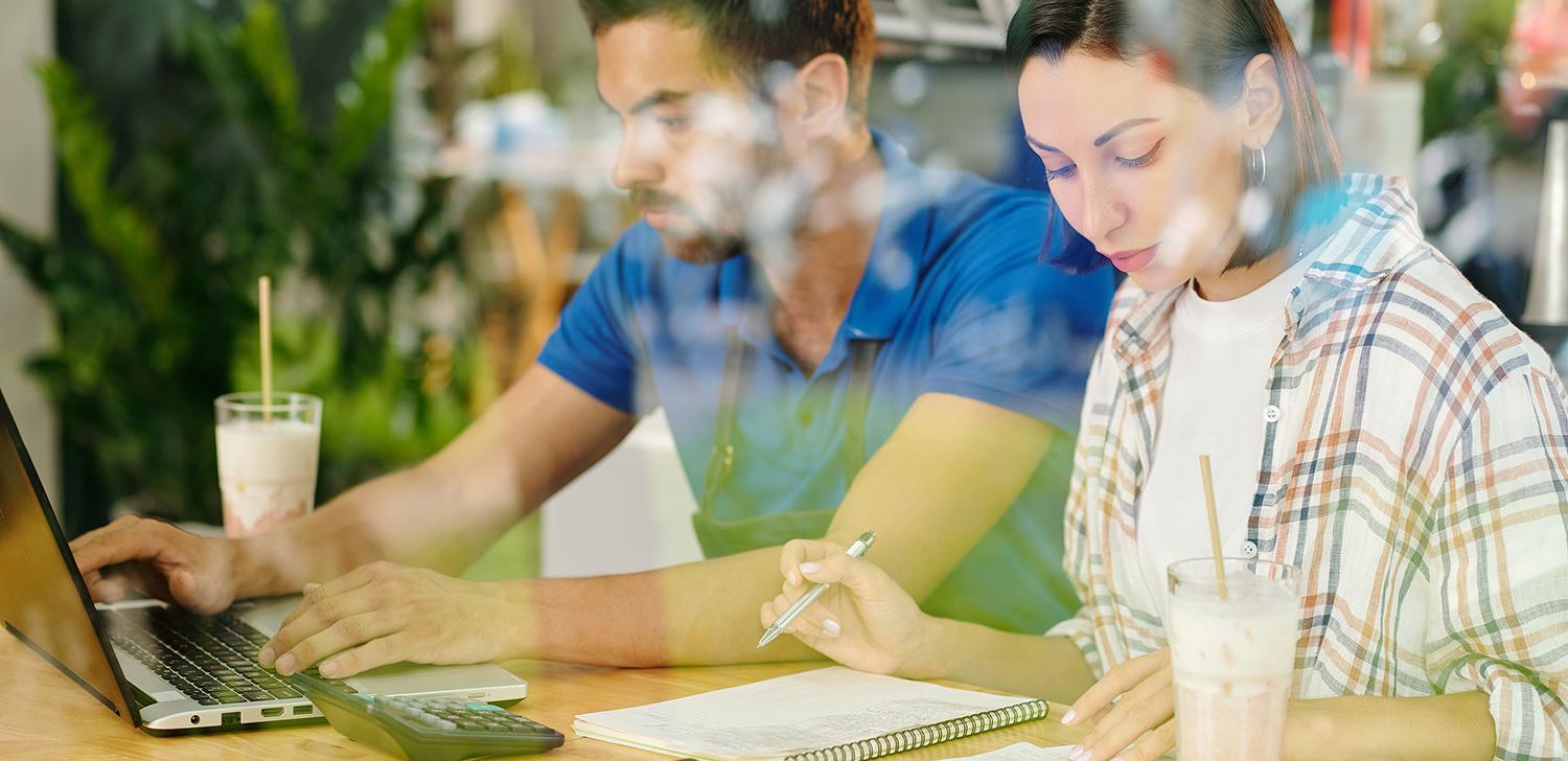 Two small business owners go over financing while sitting at a table.