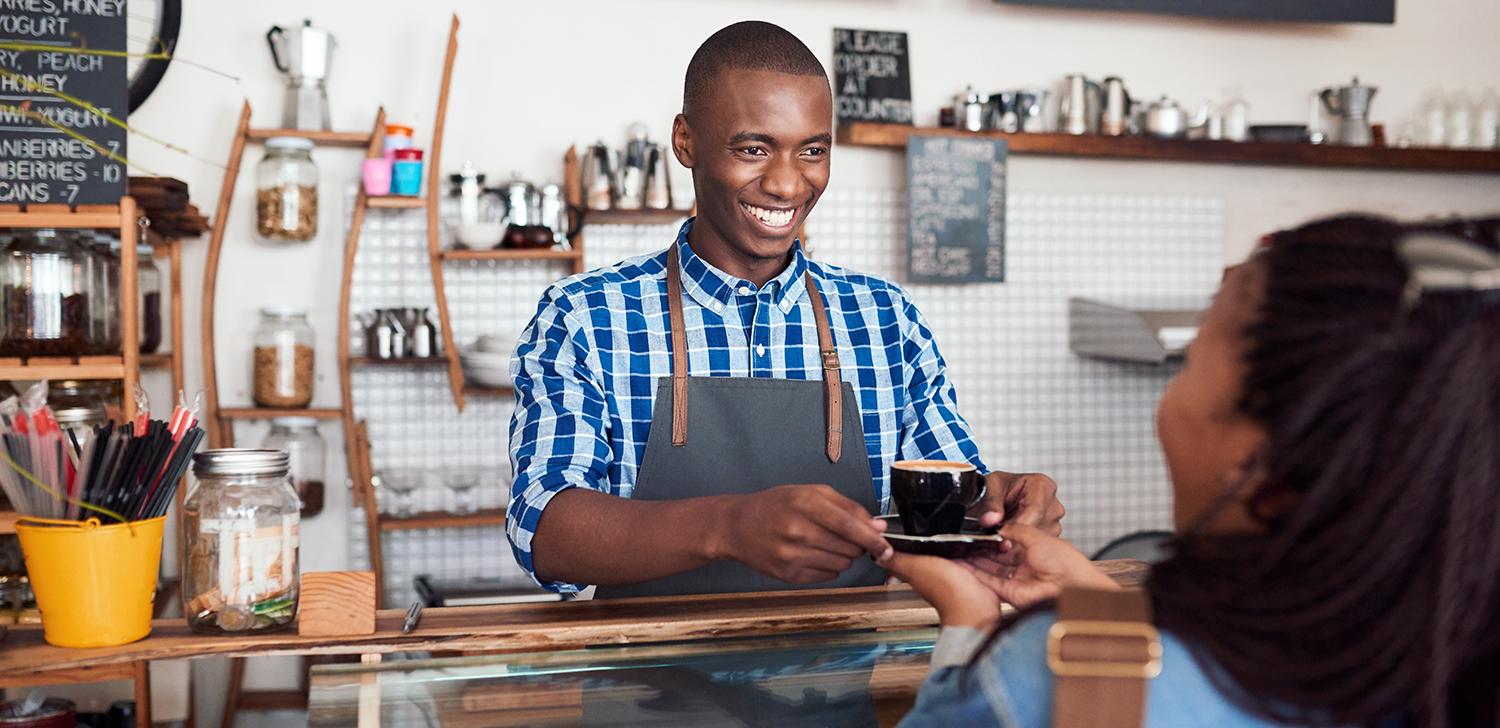 A server hands a cup of coffee to a customer.