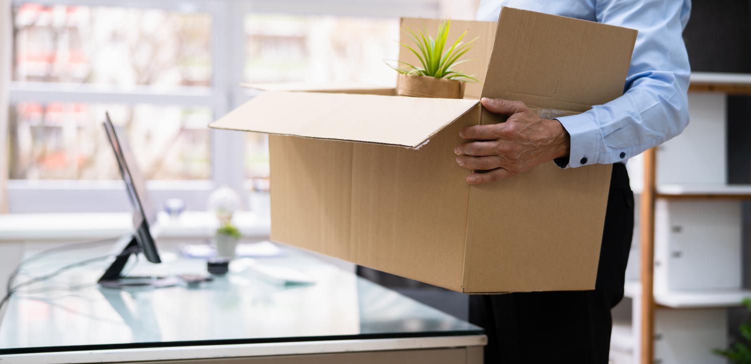 man packing up desk with cardboard box