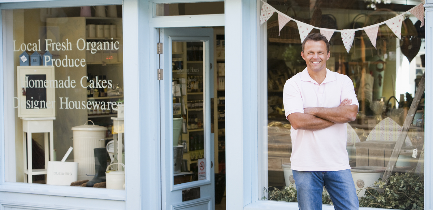 Man stating in front of small business storefront. 