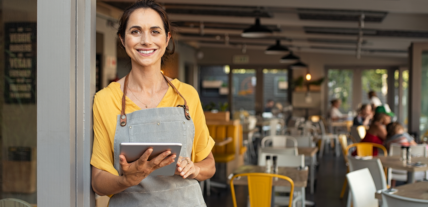Female business owner smiling in front of store.