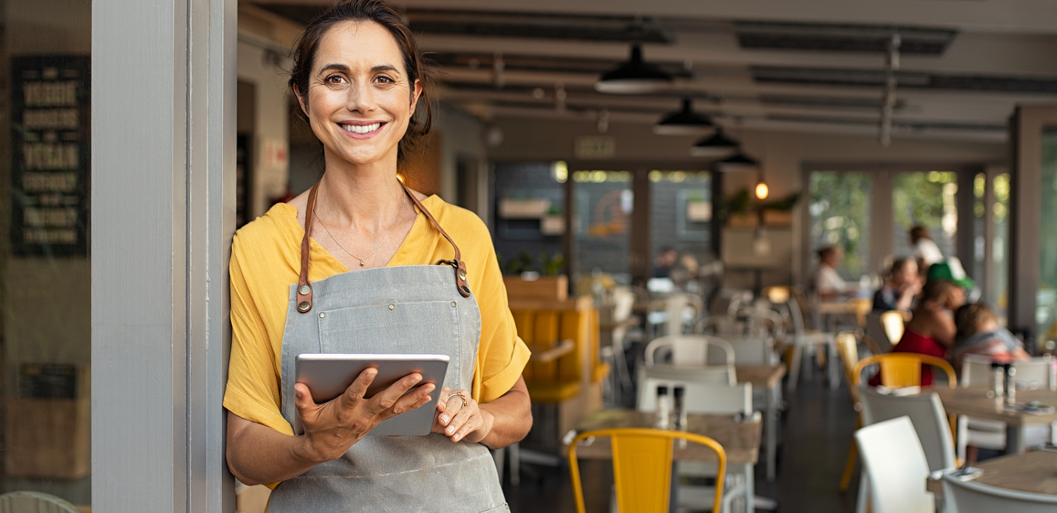 Female business owner smiling in front of store. 